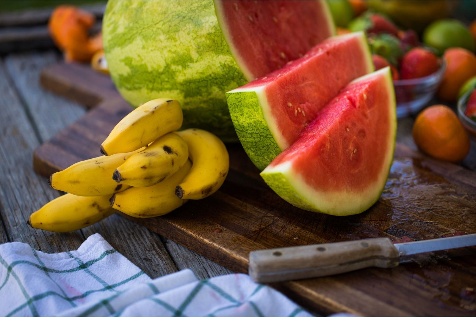 Banane bogate kalijem leže pored narezane lubenice bogate L-citrulinom na dasci za rezanje